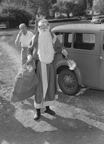 Father Christmas arrives. A man dressed as Father Christmas arrives in costume for a children's party at the Forest Inn. Possibly Nairobi, Kenya, 25 December 1952. Kenya, Eastern Africa, Africa.