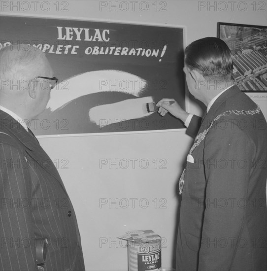 Leyland Paint Factory. A Mayor, dressed in a suit and ceremonial chain, tests a brushful of Leylac Enamel Paint at the opening of a new Leyland Paint Factory. Kenya, 12 October 1957. Kenya, Eastern Africa, Africa.