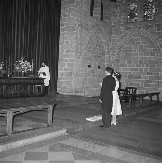 Coltart wedding. The Coltart couple read from a prayer book before the altar at their wedding ceremony. Kenya, 9 November 1957. Kenya, Eastern Africa, Africa.