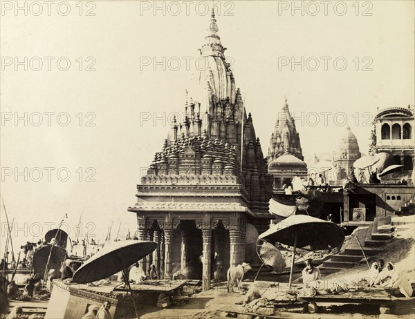 Scindia Ghat and Manikarnika Ghat. The temples of Scindia Ghat and Manikarnika Ghat, located on the banks of the River Ganges. Pilgrimage priests can be seen, seated beneath large umbrellas in the foreground. Benares, North Western Provinces (Varanasi, Uttar Pradesh), India, circa 1875. Varanasi, Uttar Pradesh, India, Southern Asia, Asia.