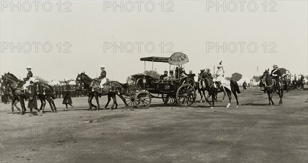 The royal couple leave for the Coronation Durbar. King George V (r.1910-36) and Queen Mary leave the royal camp for the Coronation Durbar in a horse-drawn carriage accompanied by mounted escorts. Delhi, India, circa 12 December 1911. Delhi, Delhi, India, Southern Asia, Asia.