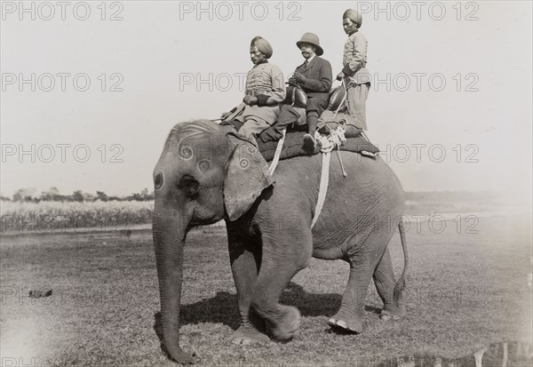 En route to a royal hunt. King George V (r.1910-36) sits on an elephant behind a mahout (elephant handler), en route to a royal hunt in Chitwan Valley. Narayani, Nepal, circa 17 December 1911., Narayani, Nepal, Southern Asia, Asia.