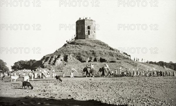 Monument near Benares. A long line of people, some riding elephants, visit an unidentified monument near Benares. The structure is likely to have some religious significance, perhaps a Hindu temple or a Buddhist stupa. Near Benares, United Provinces (Varanasi, Uttar Pradesh), India, circa 1925., Uttar Pradesh, India, Southern Asia, Asia.