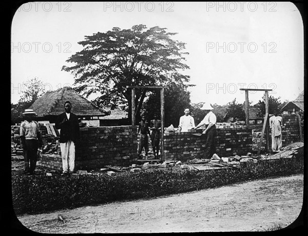 Missionaries build a chapel. European missionary workers help to build a new chapel. The burnt bricks they are using were probably reclaimed from one of the many villages destroyed to make way for new rubber plantations under King Leopold II's terror regime. Congo Free State (Democratic Republic of Congo), circa 1905. Congo, Democratic Republic of, Central Africa, Africa.