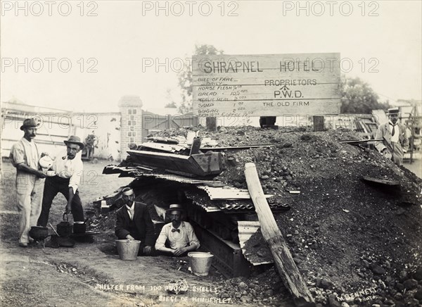 Making tea at the 'Shrapnel Hotel'. British men make tea outside a makeshift bomb shelter, jokingly named 'Shrapnel Hotel'. The shelter was built as protection against the huge shells delivered by 'Long Tom', a type of large gun used by the Boers at the Siege of Kimberley during the Second Boer War (1899-1902). Kimberley, Cape Province (North Cape), South Africa, circa December 1899. Kimberley, North Cape, South Africa, Southern Africa, Africa.