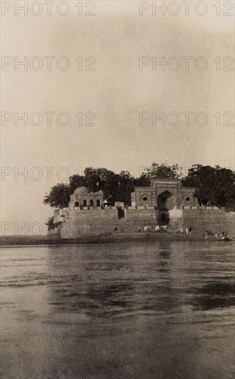 Island shrine of Khwaja Khizr. View across the Indus River looking towards to the shrine of the river saint, Khwaja Khizr. The shrine was built circa 925 AD on the island of Hajee Ka Tau, north of the Bukkur Island fort. Sukkur, Sind, India (Sindh, Pakistan), 1926. Sukkur, Sindh, Pakistan, Southern Asia, Asia.