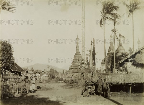 Street scene in Wuntho. A group of Wuntho townspeople mill about outside a shrine containing carved stone 'zeidis' or pagodas. This scene was captured shortly after British forces took control of Wuntho following a conflict with Burmese rebels. Wuntho, Burma (Myanmar), 1891. Wuntho, Sagaing, Burma (Myanmar), South East Asia, Asia.