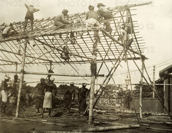 Building a spectator stand for the royal visit. A team of Ceylonian men construct the frame of a spectator stand in preparation for a visit from the Duke and Duchess of Cornwall and York (later King George V and Queen Mary). The royal couple stopped in Ceylon (Sri Lanka) on their way to open the first Commonwealth Parliament of Australia in Melbourne. Colombo, Ceylon (Sri Lanka), 1901. Colombo, West (Sri Lanka), Sri Lanka, Southern Asia, Asia.