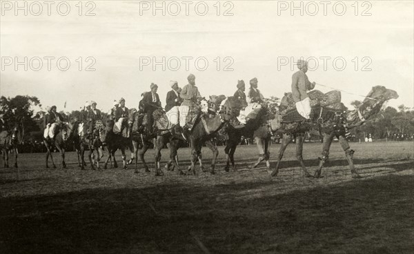 A train of Afghan camel drivers. Afghan camel drivers prepare to welcome the Duke and Duchess of Cornwall and York (later King George V and Queen Mary) to Perth. The train of turbaned men wear an array of traditional and Western dress as they ride their finely decorated camels. Perth, Australia, July 1901. Perth, West Australia, Australia, Australia, Oceania.