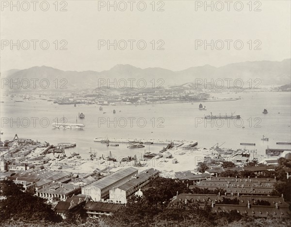 View across Victoria Harbour. A view of Victoria Harbour, taken from Hong Kong Island and overlooking the Kowloon peninsula. A Royal Navy dockyard can be seen off Hong Kong Island, where several ships of the naval fleet are moored. Hong Kong, China, 1903. Hong Kong, Hong Kong, China, People's Republic of, Eastern Asia, Asia.