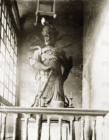 Statue of a Joss. Statue of a Chinese deity (a 'Joss'), located in a Joss house in Hong Kong. The figure is depicted as a warrier, wearing a crown and armour, and holding a sword. Hong Kong, China, circa 1903., Hong Kong, China, People's Republic of, Eastern Asia, Asia.