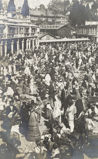 Street bazaar in Darjeeling. Crowds throng a busy street bazaar in Darjeeling. Street traders vie for business, selling goods ranging from baskets to food to customers who weave in and out of the marketplace. Darjeeling, India, circa 1922. Darjeeling, West Bengal, India, Southern Asia, Asia.