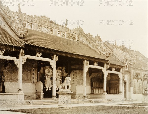 Entrance to a Hong Kong Joss house. Exterior view of a Hong Kong Joss house (Chinese temple). The front entrance of the building is guarded by the statue of a lion: its roof, adorned with decorative stone carvings depicting religious scenes and idols. Hong Kong, China, circa 1905., Hong Kong, China, People's Republic of, Eastern Asia, Asia.