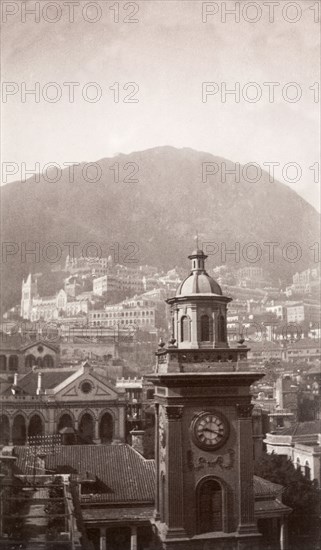 A clock tower in Hong Kong. View over Hong Kong looking south, featuring a prominent clock tower, possibly the Pedder Street clock tower, in the foreground. Hong Kong, China, circa 1905. Hong Kong, Hong Kong, China, People's Republic of, Eastern Asia, Asia.