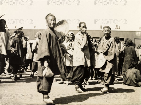 Women at a station on the Peking to Hankow railway line. Three Chinese women gaze curiously into the camera at a railway station on the Peking (Beijing) to Hankow (Hankou) railway line. Their feet have been bound, a practice that was ended in 1911 by the new Republic of China. Eastern China, circa 1910. China, People's Republic of, Eastern Asia, Asia.