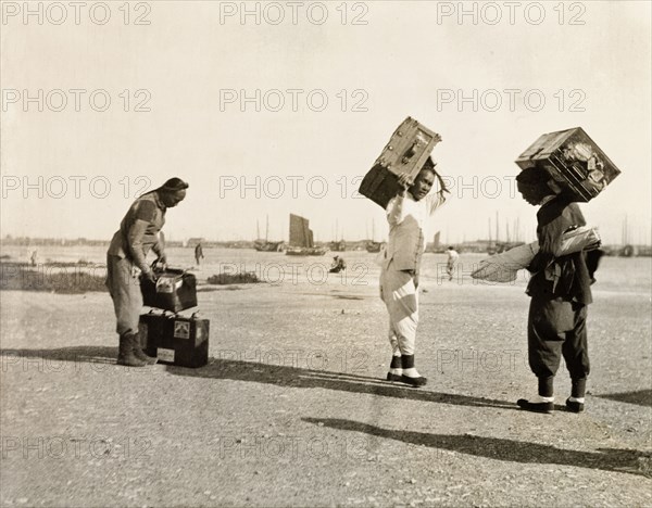 Luggage handlers at Newchwang port. Three luggage handlers prepare to load suitcases onto a waiting ferry at Newchwang (Yingkou) port. Newchwang (Yingkou), Liaoning Province, China, circa 1920. Yingkou, Liaoning, China, People's Republic of, Eastern Asia, Asia.