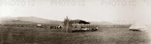 Camp site near Louis Trichardt. A makeshift thatched canopy stands in the centre of a camp site near Louis Trichardt, sheltering a long dining table and chairs from the elements. Near Louis Trichardt, Northern Transvaal (Makhado, Limpopo), South Africa, 17 October 1905. Makhado, Limpopo, South Africa, Southern Africa, Africa.