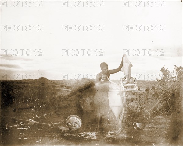 Matabele woman using a mangle. A Matabele (Ndebele) woman uses a mangle to wring water from a piece of cloth at Cecil Rhodes' farm in Sauerdale. Rhodes bought the farm after negotiating an end to the Matabele rebellion, and settled some Matabele people there in part fulfilment of a promise to provide them with decent land. Near Bulawayo, Rhodesia (Zimbabwe), circa 1897., Matabeleland North, Zimbabwe, Southern Africa, Africa.