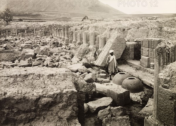 Avantisvami Temple at Avantipur. A man stands by two large clay pots amidst the ruins of Avantisvami Temple at Avantipur. The Hindu temple was built during the reign of King Avantivarman (r.855-883AD) and was dedicated to Lord Vishnu. Avantipur, Jammu and Kashmir State, India, circa 1925. Avantipur, Jammu and Kashmir, India, Southern Asia, Asia.