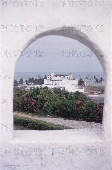 Elmina Castle from Fort St Jago. Distant view of Elmina Castle, taken through a cannon hole at Fort St Jago. Elmina, Ghana, circa 1959. Elmina, Central (Ghana), Ghana, Western Africa, Africa.