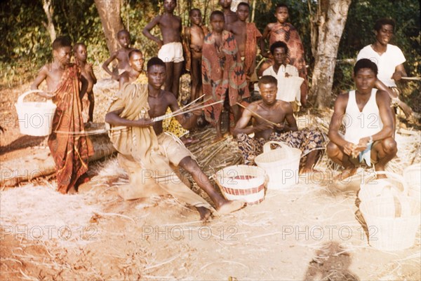 Ghanaian basketweavers. A group of craftsmen sit on the ground as they weave baskets outdoors. Bobikuma, Ghana, circa 1958. Bobikuma, Central (Ghana), Ghana, Western Africa, Africa.