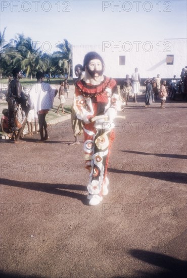 A performing masquerader. A costumed masquerader performs at an outdoor ceremony to celebrate Ghana becoming a Republic under the leadership of President Kwame Nkrumah (1909-1972). Saltpond, Ghana, 1 July 1960. Saltpond, West (Ghana), Ghana, Western Africa, Africa.