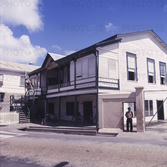 Central Police Station in Belize. A policeman stands outside the central Police Station in Belize City. Several bicycles are parked on the veranda of the colonial-style building, which is decorated with a union jack flag. Belize City, Belize, circa 1975. Belize, Belize, Belize, Central America, North America .