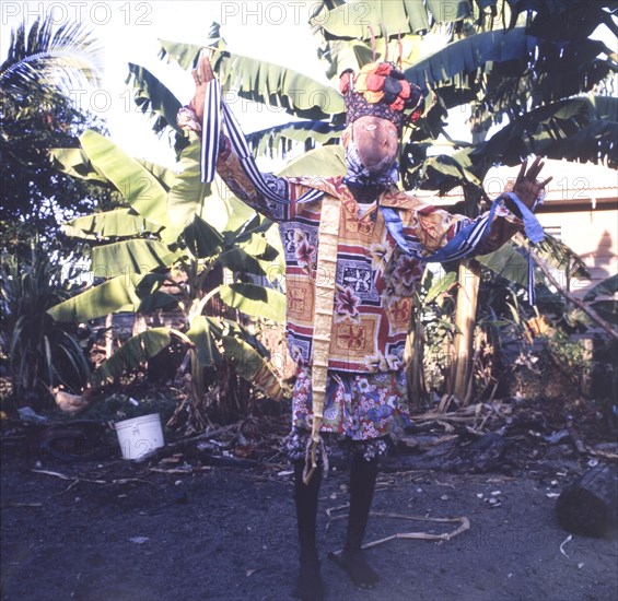 A Carib dancer in Belize. A Carib dancer performs a dance wearing a colourful costume, a painted mask and a decorative headdress. Belize, circa 1975. Belize, Central America, North America .