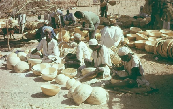 Hausa potters decorating bowls. A group of Hausa potters sit outdoors, using metal tools to inscribe patterns onto clay bowls. Kano, Nigeria, circa 1975. Kano, Kano, Nigeria, Western Africa, Africa.