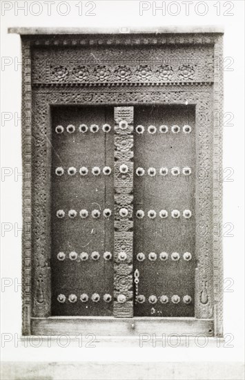 An ornate doorway in Kenya. An ornate wooden door in Lamu, decorated with studs and an intricately carved frame. Lamu, Kenya, circa 1947. Lamu, Coast, Kenya, Eastern Africa, Africa.