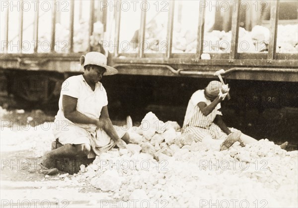 Women breaking up rocks, Jamaica. Two female labourers sit amidst a pile of rocks, breaking large stones into smaller pieces using hammers. Kingston, Jamaica, circa 1925. Kingston, Kingston, Jamaica, Caribbean, North America .