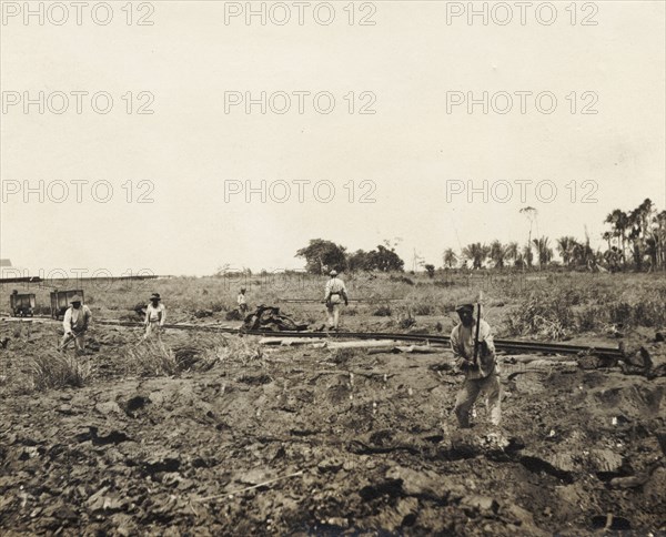 Labourers dig asphalt at the Pitch Lake. Labourers use pickaxes to extract lumps of asphalt from the Pitch Lake, a natural asphalt lake located on Trinidad's west coast. La Brea, Trinidad, circa 1912. La Brea, Trinidad and Tobago, Trinidad and Tobago, Caribbean, North America .