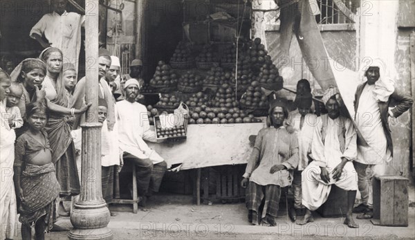 A vegetable stall in Hyderabad. Men, women and children pose for the camera beside a street stall selling heaps of vegetables. Hyderabad, Andhra Pradesh, India, circa 1930. Hyderabad, Andhra Pradesh, India, Southern Asia, Asia.