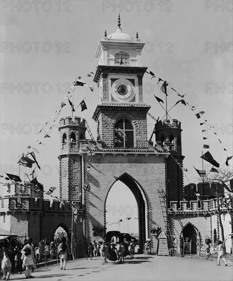 The Delhi Gate. An welcome arch identified as the 'Delhi Gate' is festooned with strings of bunting and union jack flags on a busy road in the centre of town. Hyderabad, India, circa 1905. Hyderabad, Andhra Pradesh, India, Southern Asia, Asia.