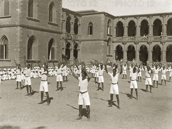 Exercises at Gordon College. African students exercise in an outdoor courtyard during an inspection visit by Sir Rudolf Carl von Slatin. The students wear matching uniforms of T-shirts and shorts, and stand in regimented rows with their hands held in the air. Khartoum, Sudan, 1926. Khartoum, Khartoum, Sudan, Eastern Africa, Africa.