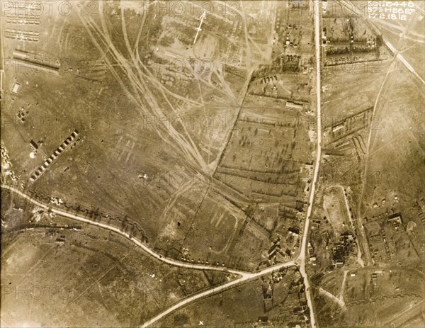 Aerial view of a camoflauge depot. One of a series of British aerial reconnaissance photographs recording the positions of trenches on the Western Front during the First World War. Square-toothed trenches surround a bomb-damaged village. An original caption indicates the position of a camouflage depot and train in the bottom left hand corner. Nord-Pas de Calais or Picardie, France, 17 February 1918., Nord-Pas de Calais, France, Western Europe, Europe .