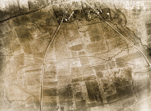 Aerial view of a bomb-damaged village. One of a series of British aerial reconnaissance photographs recording the positions of trenches on the Western Front during the First World War. Trenches zig-zag their way across fields pockmarked with bomb craters on the outskirts of a small village. An original caption indicates the position of a British Field Battery Company, located on a sunken road to the south. Nord-Pas de Calais or Picardie, France, 21 February 1918., Nord-Pas de Calais, France, Western Europe, Europe .