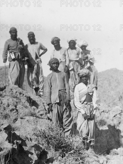 Indian men in the mountains. A group of Indian men pose for the camera on a rocky outcrop in the mountains. All wear traditional dress, including 'dhotis' and turbans. India (Pakistan), circa 1910. Pakistan, Southern Asia, Asia.