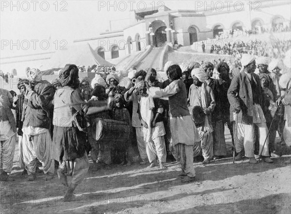 A display of swordsmanship. Musicians play as two swordsmen spar at an outdoor event. Sukkur, Sind, India (Sindh, Pakistan), circa 1908. Sukkur, Sindh, Pakistan, Southern Asia, Asia.