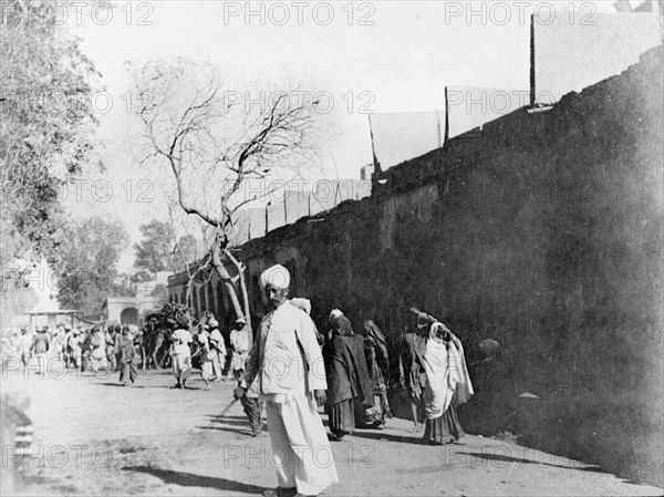 Street scene in Sukkur. People walk to and fro along a wide street in Sukkur. Sukkur, Sindh, India (Pakistan), circa 1908. Sukkur, Sindh, Pakistan, Southern Asia, Asia.