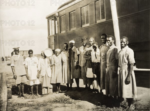 Railway servants beside a private carriage. African railway servants pose for a group portrait outside a railway carriage marked 'Private'. Probably Nyasaland (Malawi), circa 1940. Malawi, Southern Africa, Africa.