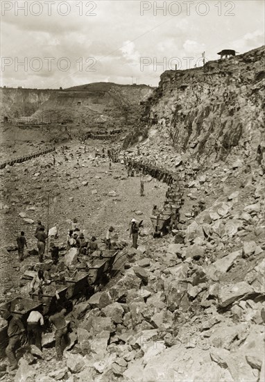 Rail carts at the Premier Diamond Mine. African labourers load rail carts full of rubble at the bottom of an open pit at the Premier Diamond Mine. Cullinan, South Africa, circa 1907. Cullinan, Gauteng, South Africa, Southern Africa, Africa.