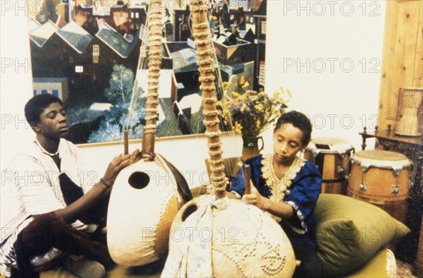 Musicians at the West African Music Village. Two young musicians adjust the strings of their lutes at the West African Music Village, a cultural festival held at the Commonwealth Institute. London, England, 1989. London, London, City of, England (United Kingdom), Western Europe, Europe .