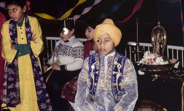 Boy in traditional Indian dress. A young turbaned boy in traditional Indian dress attends a cultural festival held at the Commonwealth Institute. London, England, circa 1985. London, London, City of, England (United Kingdom), Western Europe, Europe .