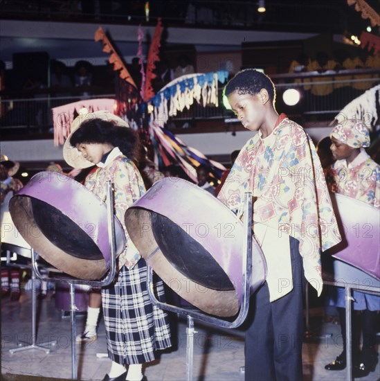 Children playing steelpans. Two Trinidadian children play steelpans on stage during a cultural festival held at the Commonwealth Institute. London, England, circa 1985. London, London, City of, England (United Kingdom), Western Europe, Europe .