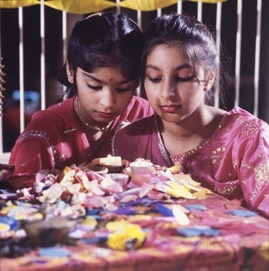 Candles for Diwali. Two girls in traditional Indian dress light candles for Diwali, the Hindu festival of light, during a mela (fair) at the Commonwealth Institute. London, England, circa 1985. London, London, City of, England (United Kingdom), Western Europe, Europe .