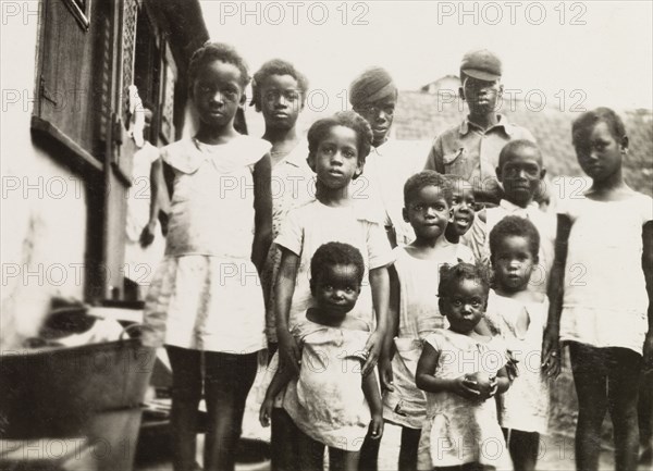 Trinidadian children. A group of Trinidadian children, ranging from toddlers to teenagers, pose for an informal portrait on a city street. Port of Spain, Trinidad, circa 1931. Port of Spain, Trinidad and Tobago, Trinidad and Tobago, Caribbean, North America .