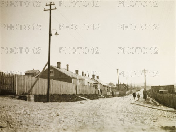 Stanley, East Falkland. View down a gravel road stretching past a row of colonial-style houses and into the distance. Stanley, Falkland Islands, circa 1931. Stanley, East Falkland, Falkland Islands, South Atlantic Ocean, South America .