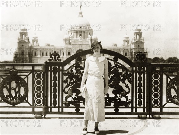 Posing outside Victoria Memorial Hall. A European woman poses in front of the ornate gateway to Victoria Memorial Hall, an imperial building built to commemorate Queen Victoria. Completed in 1921, it was designed by British architect Sir William Emerson in a fusion of European and Mughal architectural style. Calcutta (Kolkata), India, April 1935. Kolkata, West Bengal, India, Southern Asia, Asia.