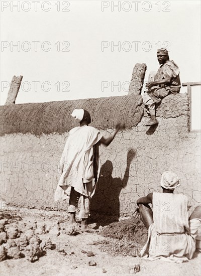 Construction of a new school in Kano. Nigerian builders put the finishing touches to a mud wall during the construction of a new school. Kano, Nigeria, 1914. Kano, Kano, Nigeria, Western Africa, Africa.